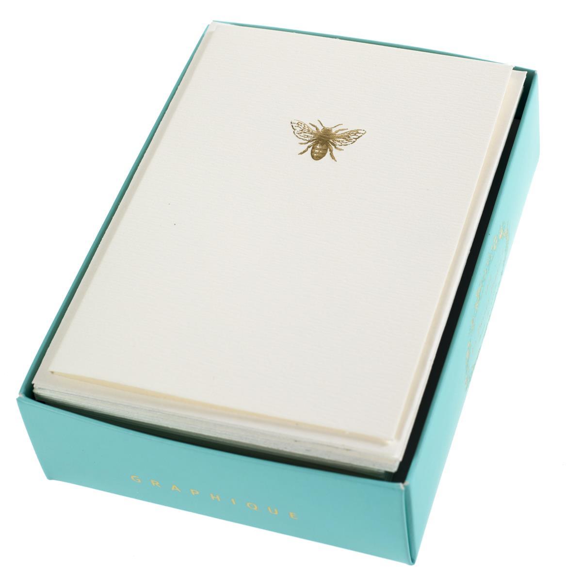 La Petite Presse Bee Boxed Notes, A cream notecard with a single gold foil bee icon, tied with a gold ribbon inside a teal box.