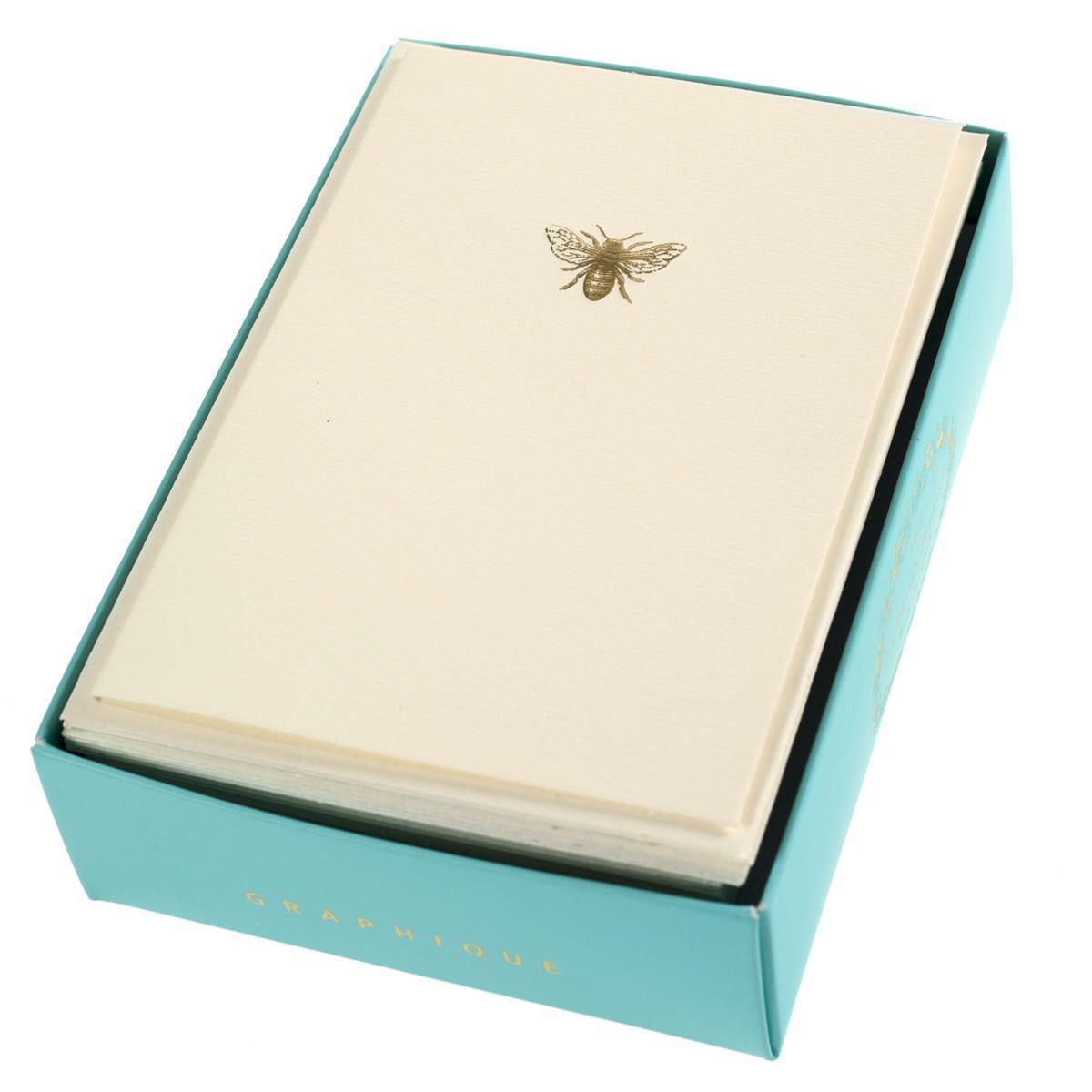 La Petite Presse Bee Boxed Notes, A cream notecard with a single gold foil bee icon, tied with a gold ribbon inside a teal box.
