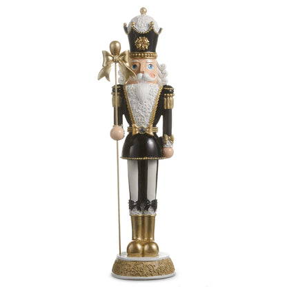 Black Bow Nutcracker, A nutcracker figure in a black and gold crown and coat with a white lace collar, black bows at the knees, gold boots, and a gold bow topped scepter, standing on a gold and white base.