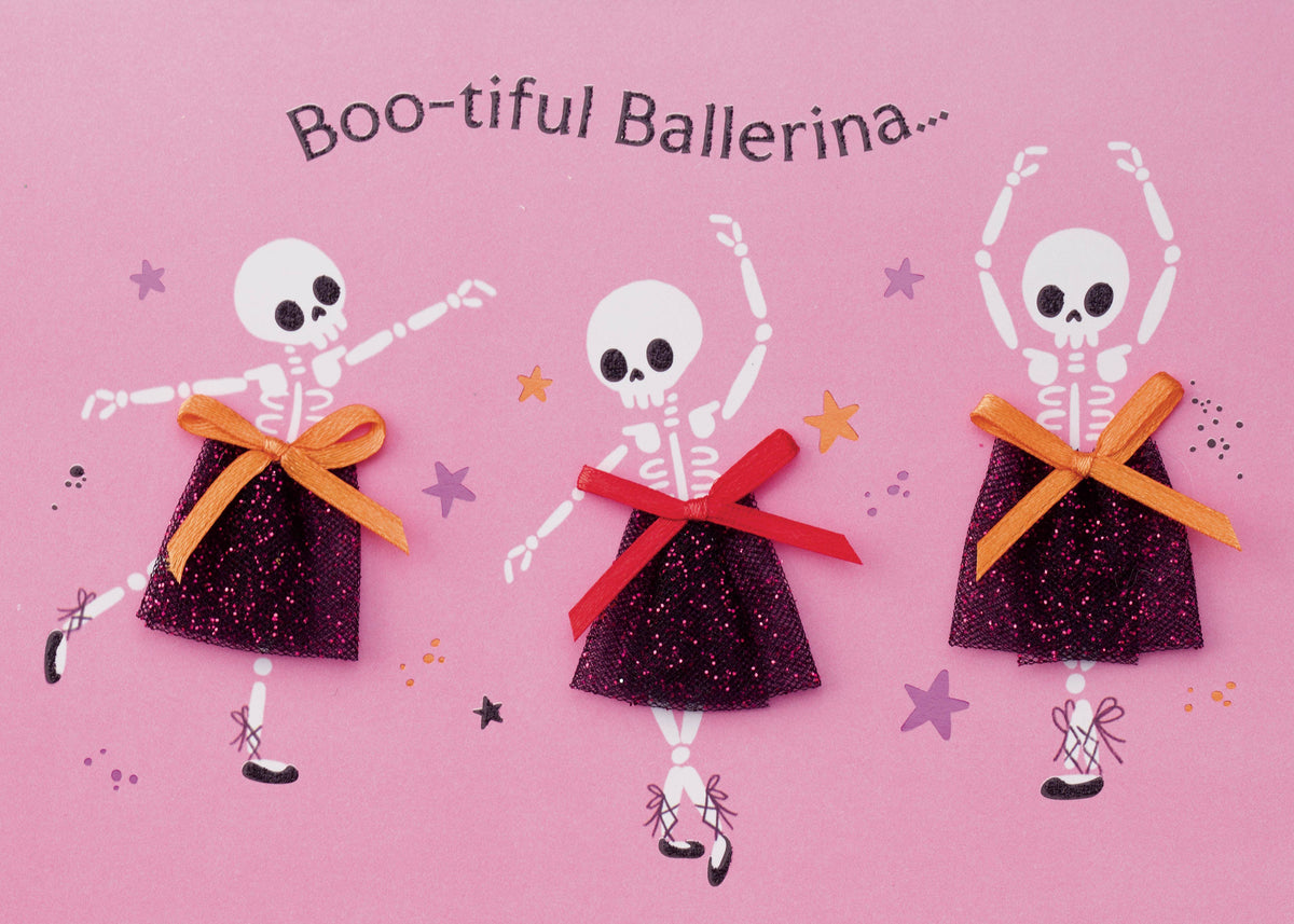 Boo-tiful Ballerina Greeting Card, Front of the card showing three skeleton ballerinas in glittery black skirts with orange and red ribbon bows on a pink ground, with the words Boo-tiful Ballerina arched above them.