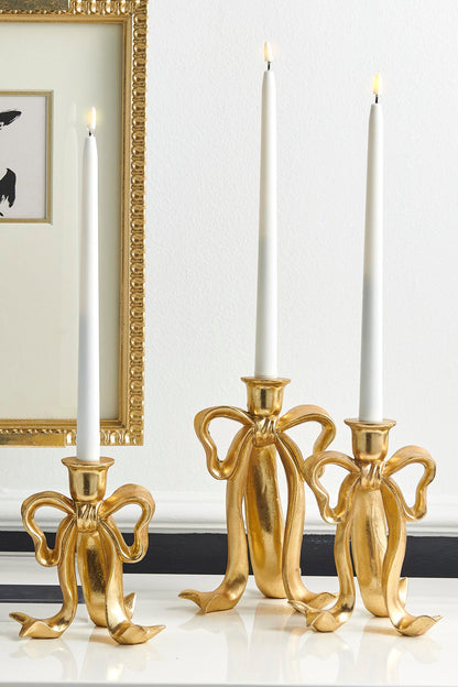 Bow Taper Candlestick, Three graduated sage green resin candlesticks shaped like tied ribbon bows, each with a taper candle holder at the top.
