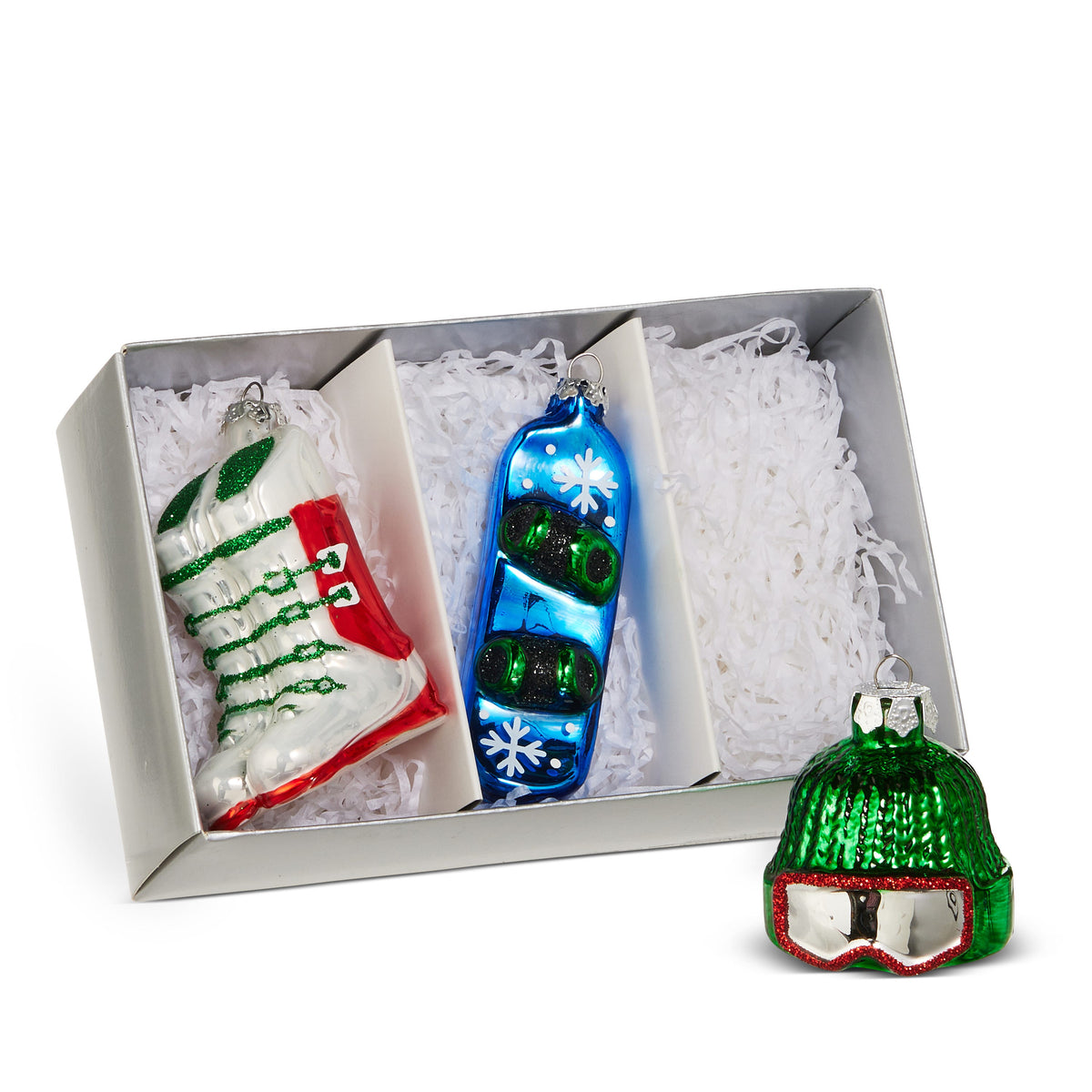 Box of Skiing Ornaments, A box of three glass ornaments shaped like an ice skate, a snowboard, and a knit ski cap with goggles.