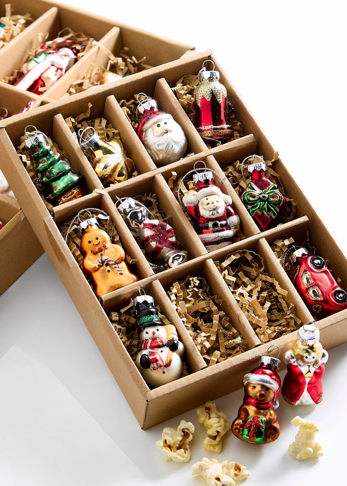 Box of Traditional Christmas Ornaments, A box of twelve miniature glass Christmas ornaments including a bear, gifts, Santa figures, a star, a snowman, an angel, a tree, and a gingerbread man, each in a padded compartment.