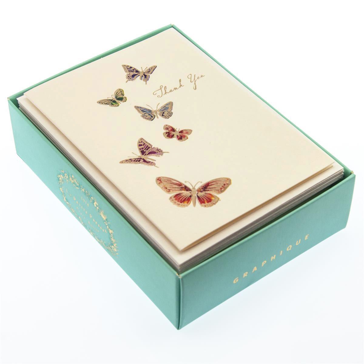 La Petite Presse Butterflies Boxed Notes, A cream Thank You card with six jeweled-tone foil butterflies rising toward gold script, tied with a tan ribbon inside a teal box.