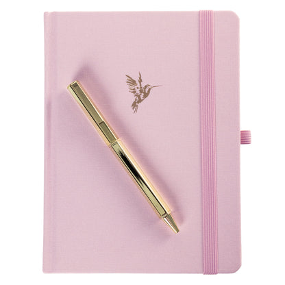La Petite Presse Hummingbird Fabric-Bound Journal with Pen, A pink fabric journal with a gold foil hummingbird on the cover, paired with a gold twist pen tucked into a loop at the spine.