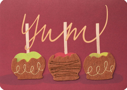 Candy Apple Yum Greeting Card, A burgundy card front with three caramel apples on white sticks, two green and one red, coated in brown felt-look caramel with stitched swirls, under the looping copper script word Yum.