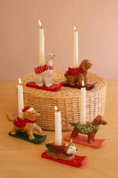 Ceramic Christmas Dog Taper Candle Holder, Five ceramic dog figures in holiday scarves, each holding a taper candle, lined up in a row.