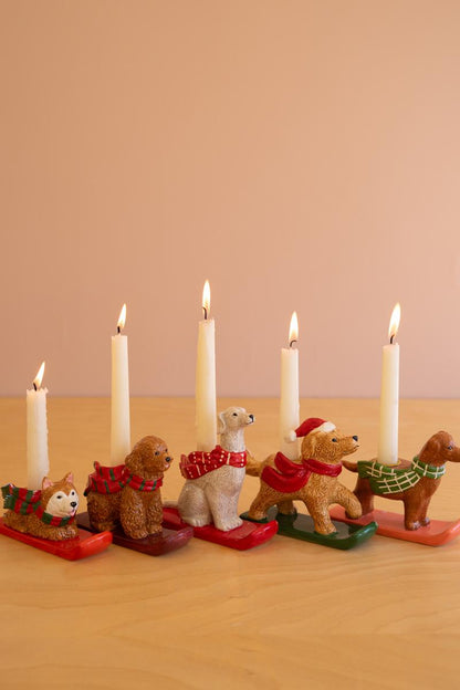 Ceramic Christmas Dog Taper Candle Holder, Five ceramic dog figures in holiday scarves, each holding a taper candle, lined up in a row.