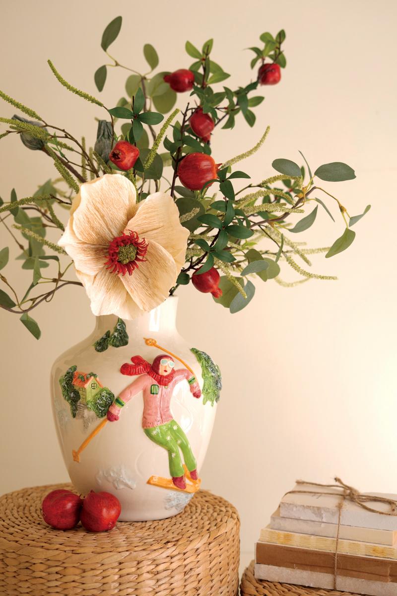 Ceramic Christmas Vase with Skier, A glossy ceramic vase with a painted skier figure wrapped around its side.