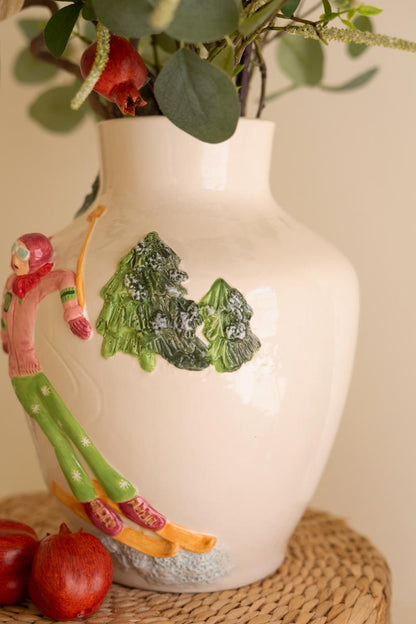 Ceramic Christmas Vase with Skier, A glossy ceramic vase with a painted skier figure wrapped around its side.