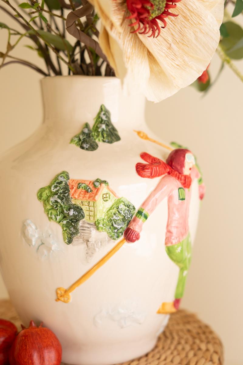 Ceramic Christmas Vase with Skier, A glossy ceramic vase with a painted skier figure wrapped around its side.