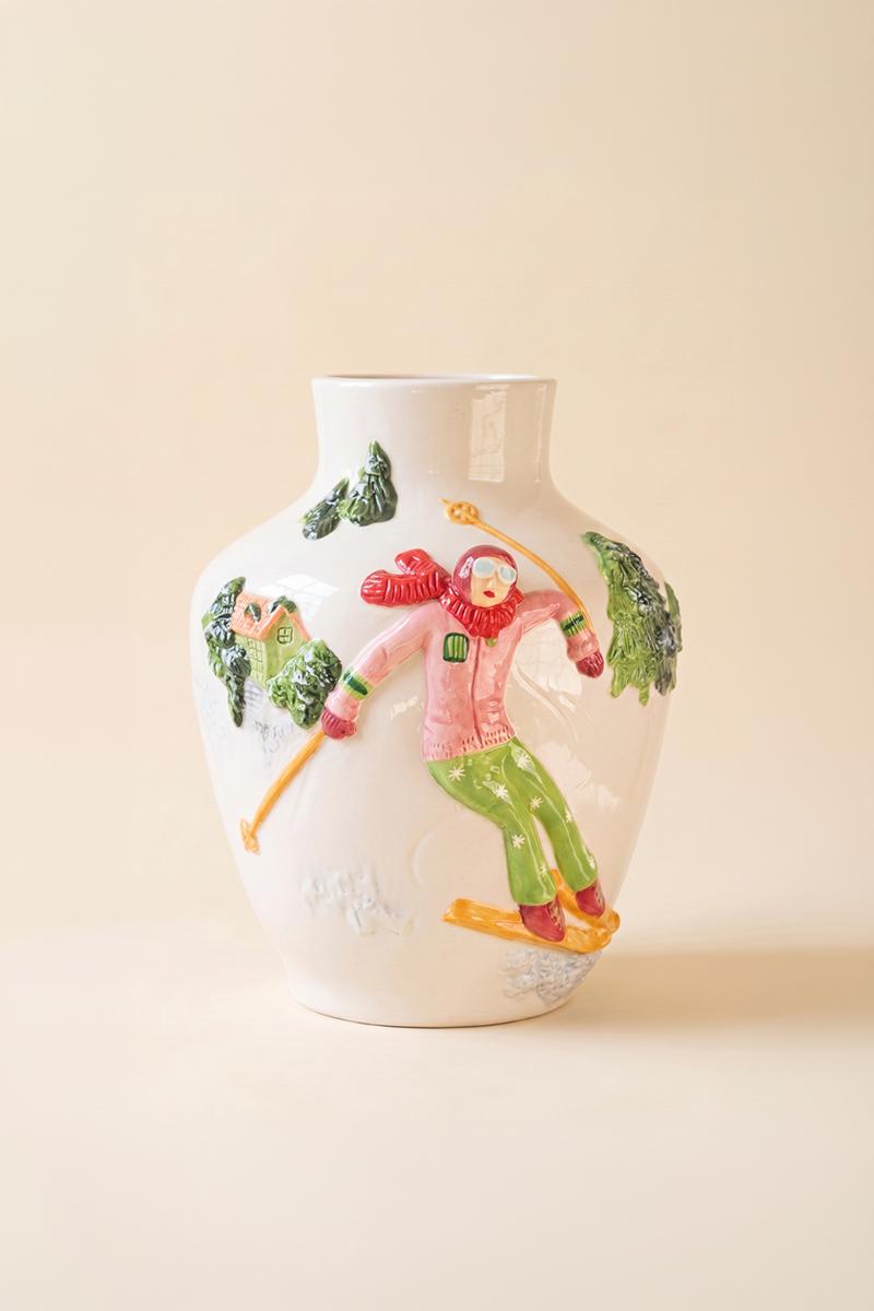 Ceramic Christmas Vase with Skier, A glossy ceramic vase with a painted skier figure wrapped around its side.