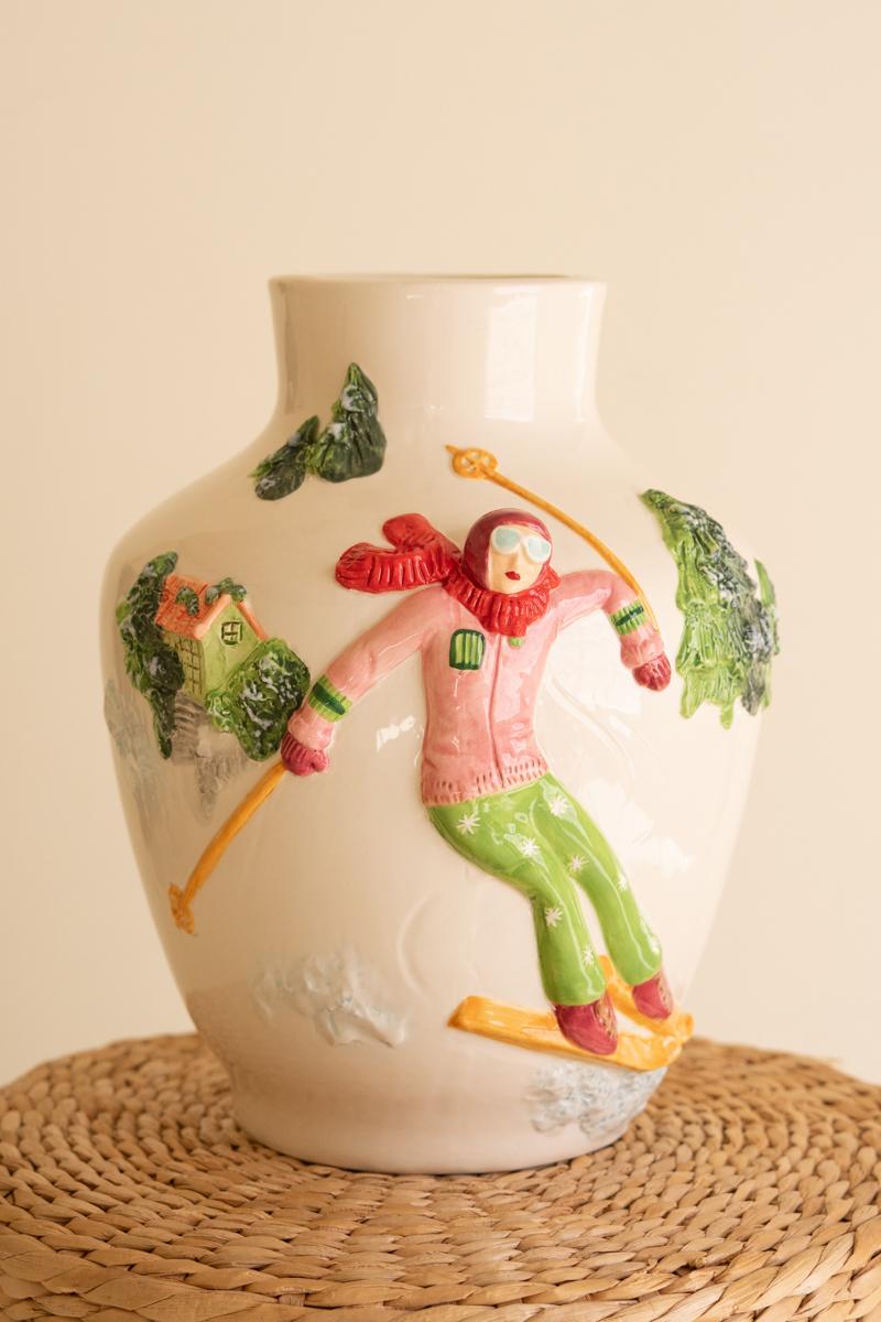 Ceramic Christmas Vase with Skier, A glossy ceramic vase with a painted skier figure wrapped around its side.