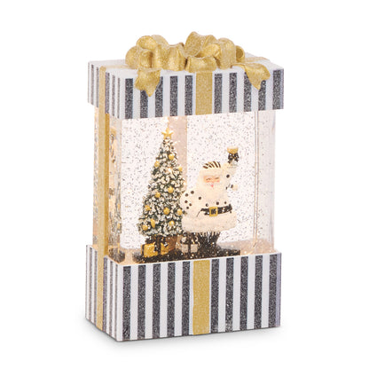 Champagne Service Santa Lighted Water Present, A black-and-white striped present-shaped lantern with a gold glitter bow, showing Santa in a white polka dot suit raising a champagne glass beside a flocked tree with gold ornaments.