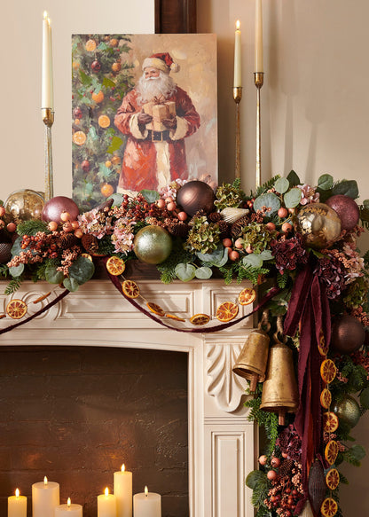 Classic Claus Santa Wood Wall Art, Wall art of a traditional Santa in a long red coat holding a wrapped gift beside a Christmas tree hung with orange slices and ornaments, with packages at his feet.