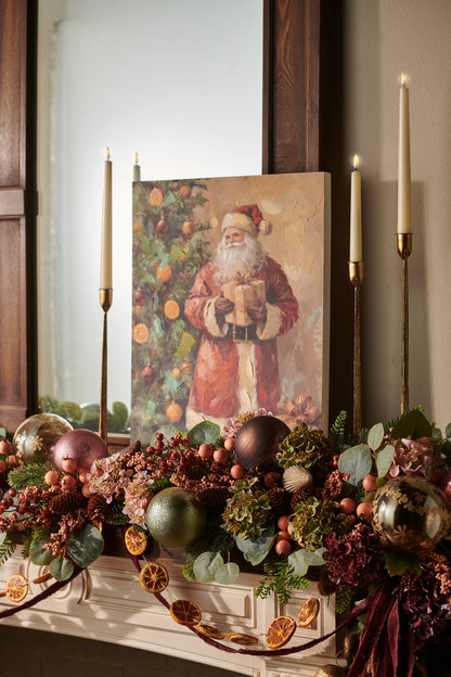 Classic Claus Santa Wood Wall Art, Wall art of a traditional Santa in a long red coat holding a wrapped gift beside a Christmas tree hung with orange slices and ornaments, with packages at his feet.
