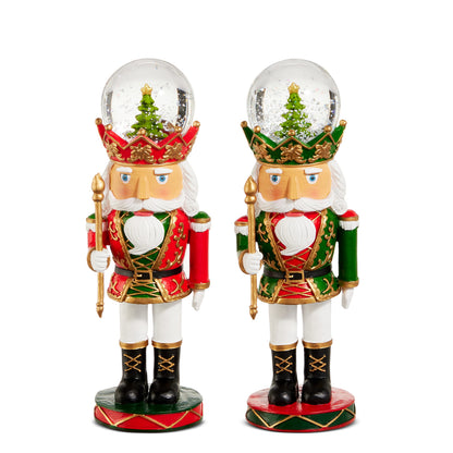 Crowned Nutcracker Water Globe, Two crowned nutcracker water globes side by side, one in a red coat and one in a green coat, each with a small evergreen tree inside the clear globe on its head.