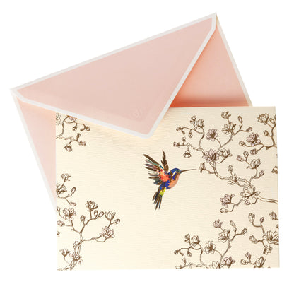 La Petite Presse Hummingbird Boxed Correspondence Notes, A cream notecard with a colorful hummingbird and gold magnolia branch line art, paired with a blush pink lined envelope.