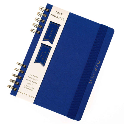 Cobalt Blue Fabric-Bound Task Journal, A cobalt blue fabric-covered task journal with gold twin wire spirals and two navy ribbon bookmark tabs, closed with an elastic band.