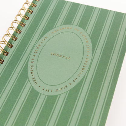 Cottage Stripe Everyday Journal, A green striped spiral-bound journal with a gold foil oval reading Dreaming of a Slow Life and Journal on the cover.
