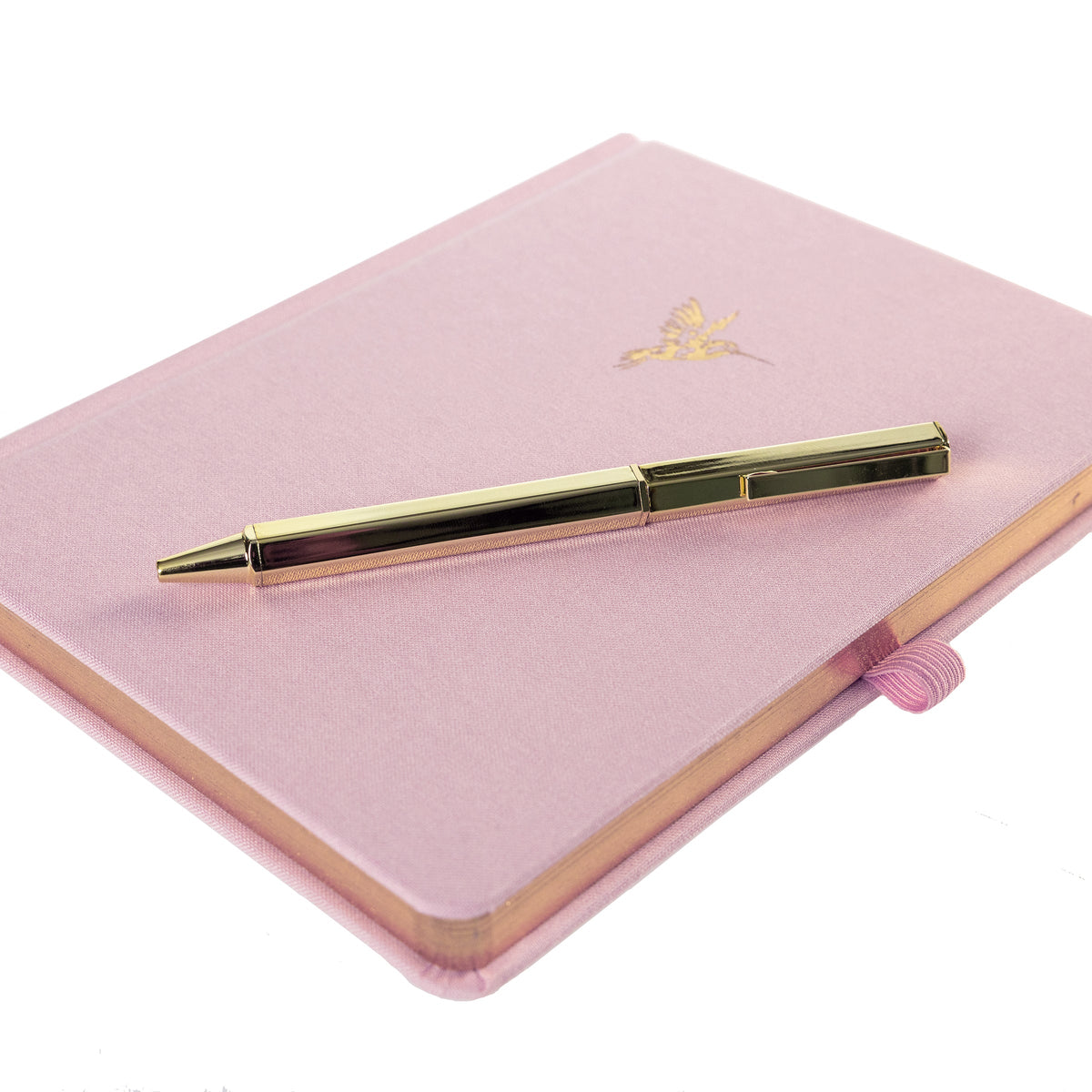 La Petite Presse Hummingbird Fabric-Bound Journal with Pen, A pink fabric journal with a gold foil hummingbird on the cover, paired with a gold twist pen tucked into a loop at the spine.