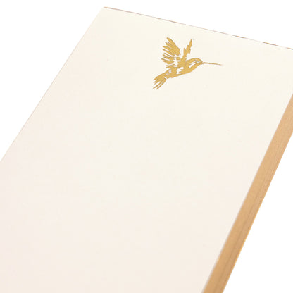 La Petite Presse Hummingbird Gilded Desktop Notepad, A cream notepad with a gold foil hummingbird at the top corner and a gold gilded edge, tied with a gold ribbon.