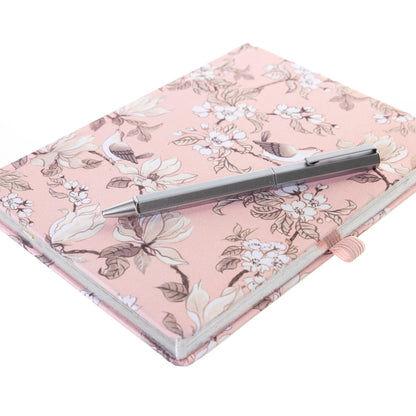 La Petite Presse Birds Fabric-Bound Journal with Pen, A blush pink fabric journal printed with songbirds and magnolia blossoms, closed with an elastic band and a silver pen tucked into a loop.
