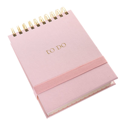Blush Fabric-Bound Notepad, A blush pink fabric notepad with a gold foil to Do cover and a twin wire spiral binding.
