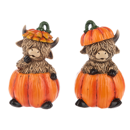 Fall Highland Cow Figurine, Two shaggy brown Highland cow figurines sitting in orange pumpkins, one in an orange petal hat and one wearing a pumpkin lid.