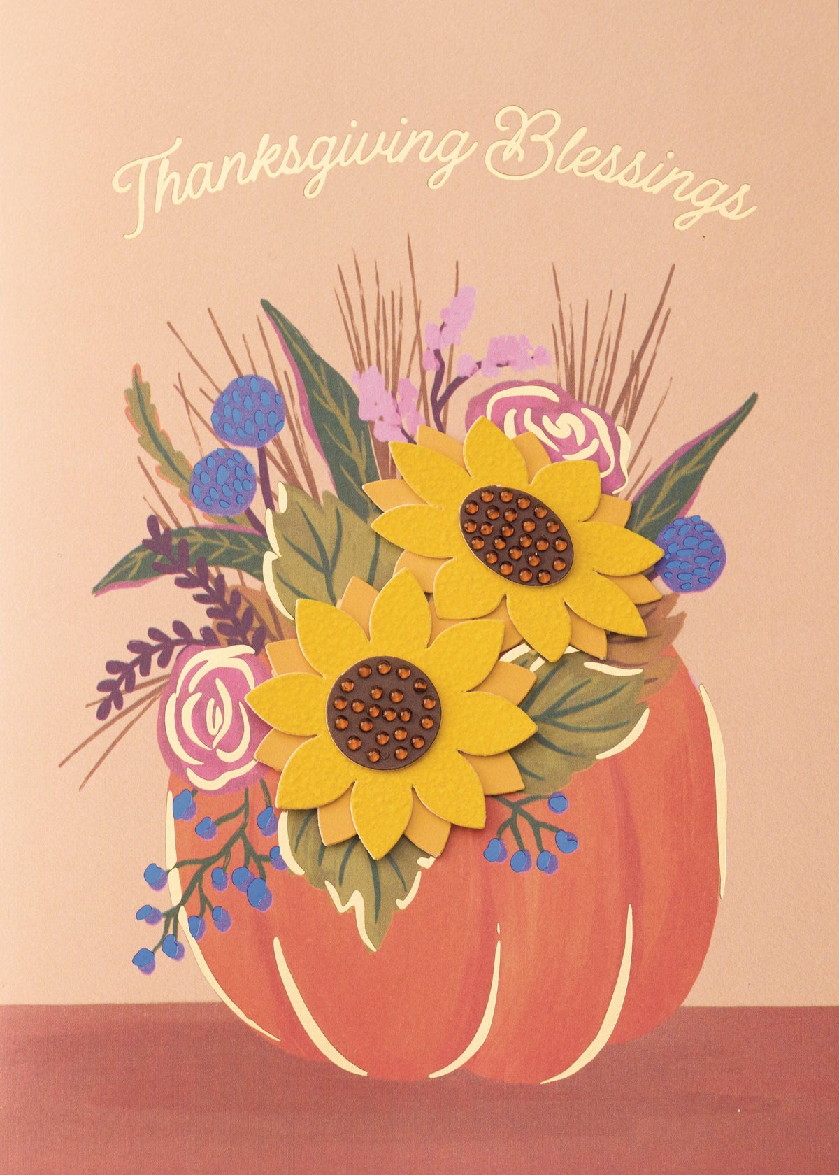Floral Unending Blessings Greeting Card, A peach card front with Thanksgiving Blessings in gold script above an orange pumpkin holding a bouquet of two layered yellow sunflowers, pink roses, blue berries and grasses.
