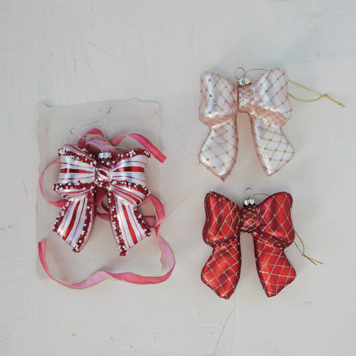 Glass Candy Striped Bow Ornament with Beads, Red and White, A glass bow ornament striped in red and white hangs by a silver cord, its ribbon ends and center knot trimmed with white and red beads and sequins.