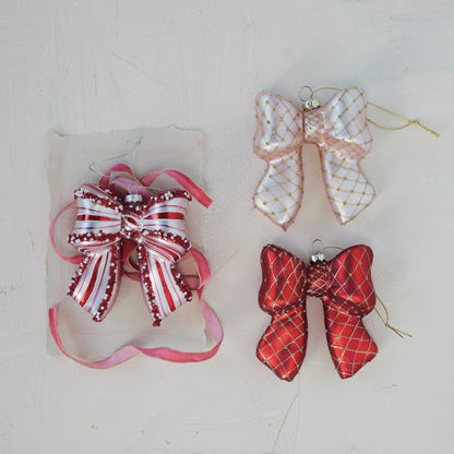 Glass Candy Striped Bow Ornament with Beads, Red and White, A glass bow ornament striped in red and white hangs by a silver cord, its ribbon ends and center knot trimmed with white and red beads and sequins.