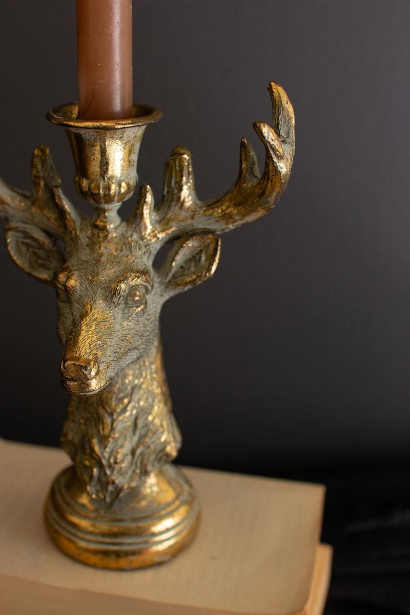 Gold Deer Resin Taper Candle Holder, A gold resin deer figure with a taper candle holder set between its antlers.