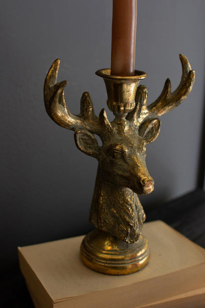 Gold Deer Resin Taper Candle Holder, A gold resin deer figure with a taper candle holder set between its antlers.