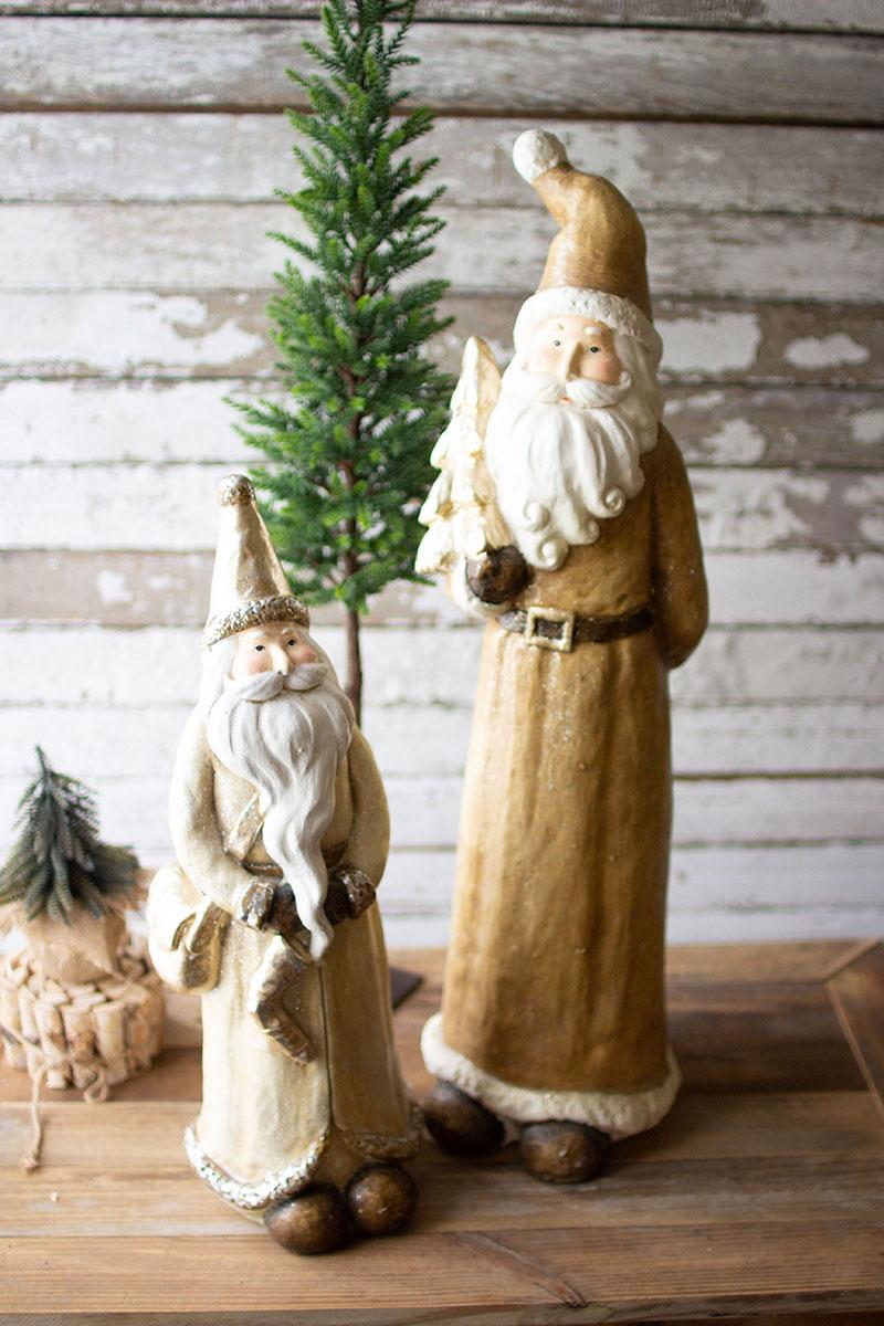 Gold Resin Santa, Two resin Santa figures in muted gold cloaks, the taller holding a small Christmas tree and the shorter holding a stocking.