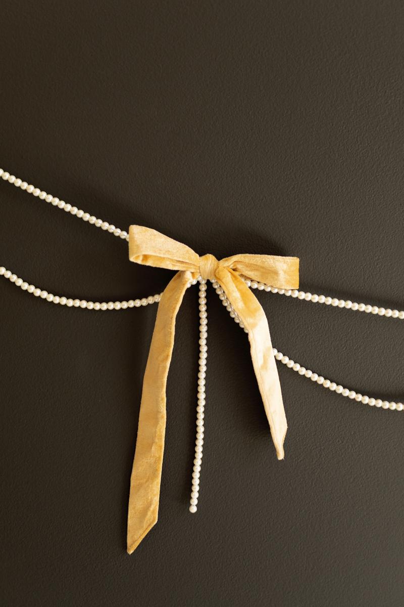 Gold Velvet Bow Garland with Faux Pearl Swag, A garland of velvet bows joined by gold rings with strands of faux pearls hanging between them.