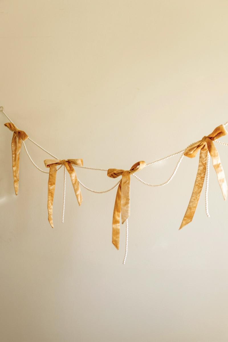 Gold Velvet Bow Garland with Faux Pearl Swag, A garland of velvet bows joined by gold rings with strands of faux pearls hanging between them.