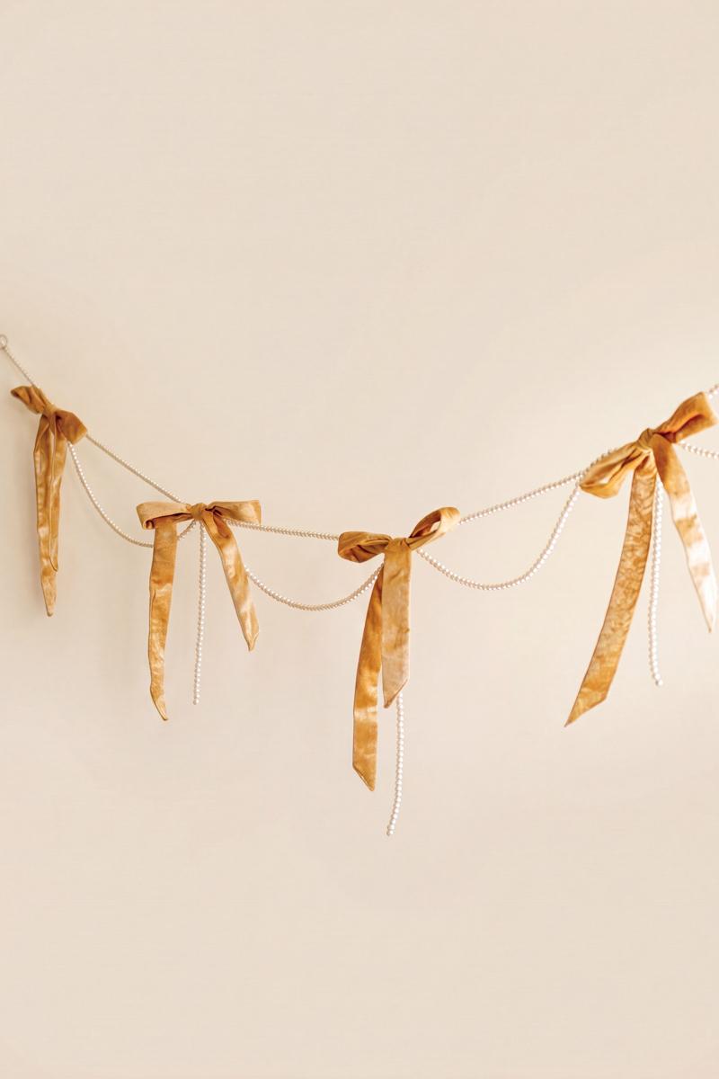 Gold Velvet Bow Garland with Faux Pearl Swag, A garland of velvet bows joined by gold rings with strands of faux pearls hanging between them.