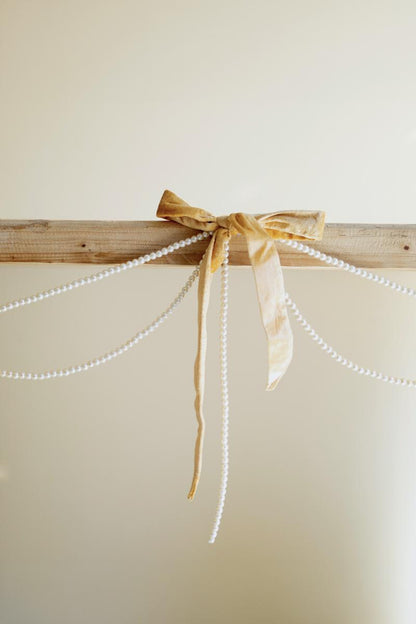 Gold Velvet Bow Garland with Faux Pearl Swag, A garland of velvet bows joined by gold rings with strands of faux pearls hanging between them.