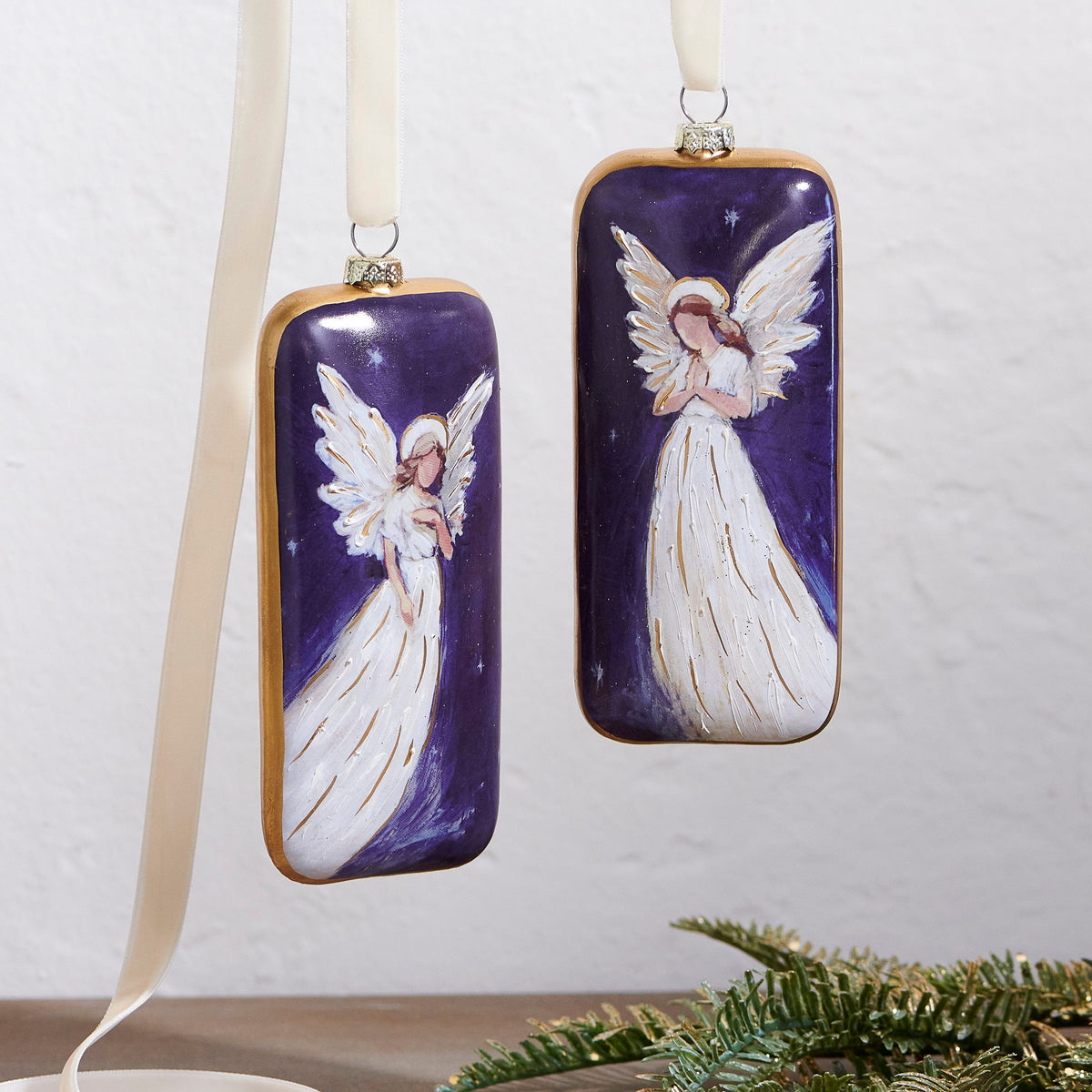 Guardian Angel Rectangle Glass Ornament, Two rectangular glass ornaments with gold edges showing white-gowned angels on a starry violet background, one with a hand on her heart and one praying.