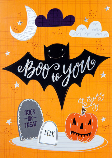 Halloween Calligraphy Bat Greeting Card, Front of a Halloween card on an orange grid background showing a smiling black bat with Boo to you in silver cursive across its wings, a crescent moon, clouds, silver stars, two tombstones and a jack-o'-lantern.