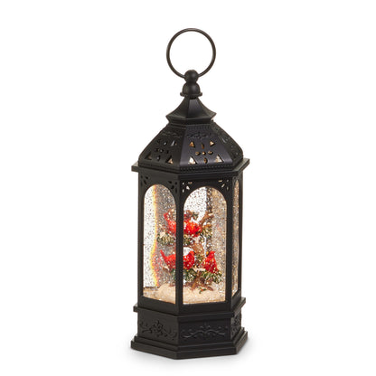 Hexagonal Cardinal Tree Lighted Water Lantern, A six-sided black water lantern with a pierced roof and ring handle, showing several red cardinals perched in a snowy tree behind glitter-filled arched windows.