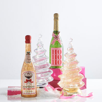 Ho Ho Ho Pink and Green Lighted Glitter Bottle, A green lighted bottle filled with green glitter, with a neck coated in gold glitter, a pink ribbon crossed under a peppermint candy, and a pink label printed with HO HO HO in red striped letters.