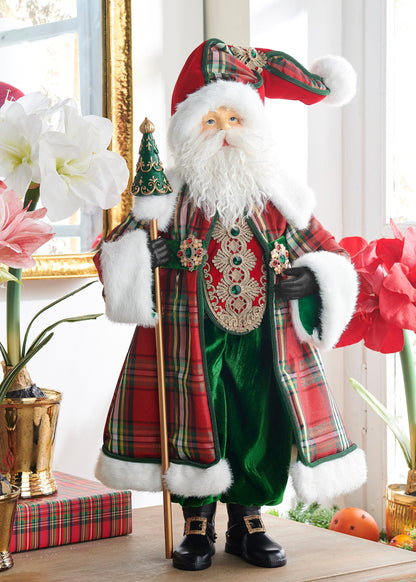 Home For The Holidays Santa, A Santa figure in a red and green tartan coat with a gold embroidered vest, green velvet trousers, and black boots, holding a gold staff topped with a small decorative tree.