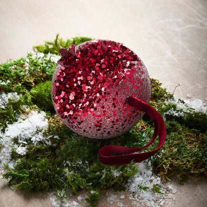 Iced Pomegranate Ornament, A red glitter ornament shaped like a pomegranate with a crowned top, hanging from a burgundy ribbon.