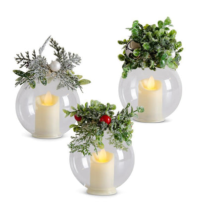 Icy LED Glass Christmas Ornament with Timer, Three clear glass globes each hold a flameless LED candle and carry an icy greenery cluster on top, one with a pearl, one with a silver bell and one with red berries.