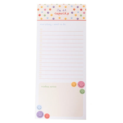 I'm At Capacity Magnetic Notepad, A tall magnetic notepad printed 'i'm at capacity' with colorful smiley polka dots above a lined checklist and a 'random notes' section.