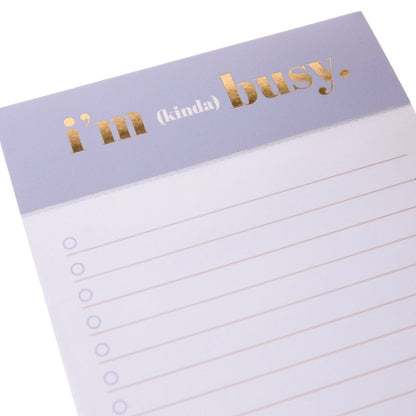 I'm Busy Jotter Notepad, A lavender-topped jotter notepad printed with 'i'm (kinda) busy' in gold foil above lined, checkbox-style pages.