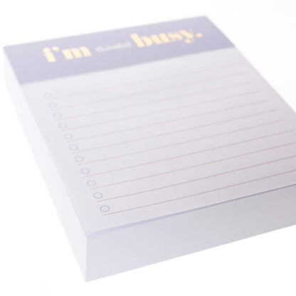I'm Busy Jotter Notepad, A lavender-topped jotter notepad printed with 'i'm (kinda) busy' in gold foil above lined, checkbox-style pages.