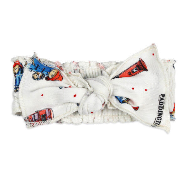 London Paddington Print Organic Smocked Baby Headband, A white smocked baby headband with a front bow featuring a colorful London Paddington themed print and a small woven Paddington label.